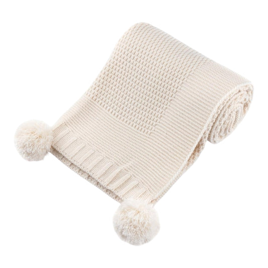Beige knitted blanket with pom-poms on a white background